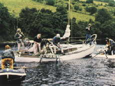 Boat and crew lowering camera equipment into water.